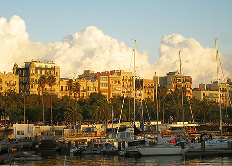 Barcelona seaport with the glow of sunlight off of the big white clouds and buildings in the background. Located Barcelona, Spain.