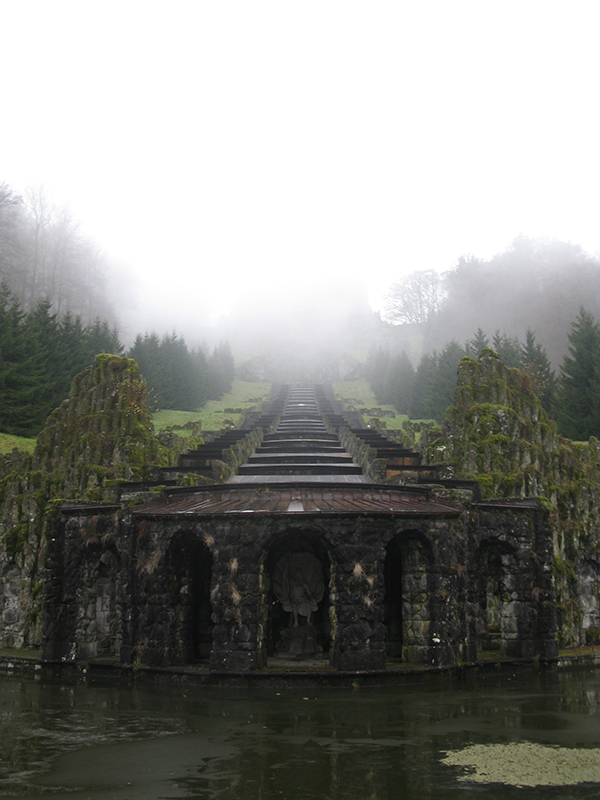 Unedited picture of Hercules monument coming down to a water area. Going from the bottom of the picture the monument is rising into a mystical fog. Located in Kassel, Germany.