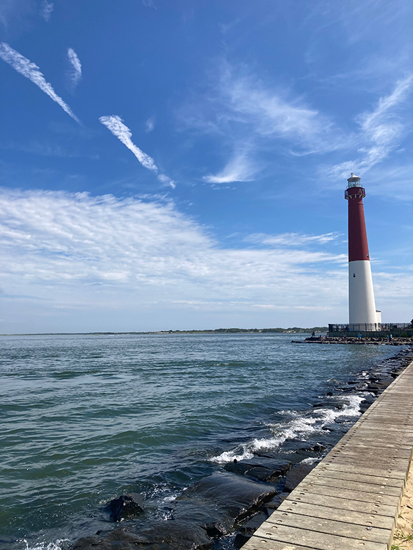 The Barnegat Lighthouse is red and white sitting on the edge of the bay on Long Beach Island, New Jersey. With blue skies.