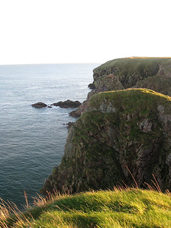 On an off beaten path located in Scotland are several high cliffs at the edge of the ocean.