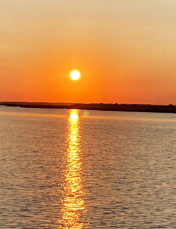 A warm orange, red glow sunset with the golden rays shimmering on the water. Picture taken at Chincoteague Island, Virginia.
